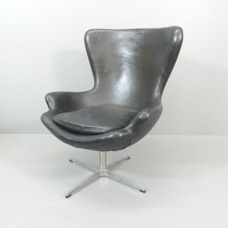 A black faux-leather upholstered egg chair in the manner of ...